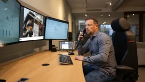 Man belt terwijl hij via WeSeeDo op zijn scherm een brandend gebouw ziet, symbool voor snelle visuele communicatie bij incidenten.