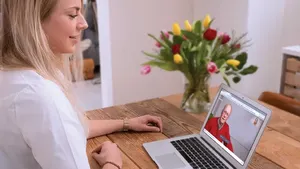 Vrouw achter de computer beeldbelt via WeSeeDo aan de keukentafel.