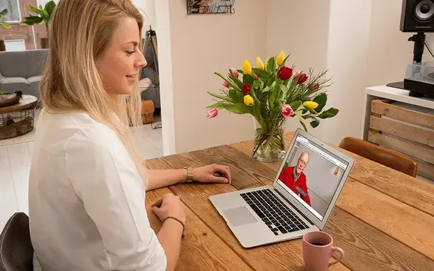 Vrouw beeldbelt met een oudere man via WeSeeDo, illustratie van de samenwerking met PharmaPartners voor veilig beeldbellen in de zorg.