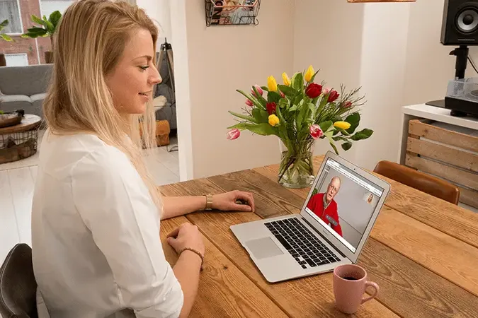 Vrouw beeldbelt met een oudere man via WeSeeDo, illustratie van de samenwerking met PharmaPartners voor veilig beeldbellen in de zorg.
