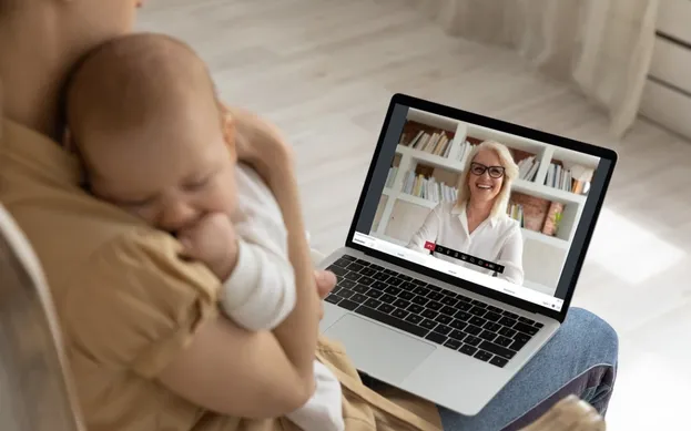 Moeder met net geboren baby aan het videobellen op een Ipad met de kraamverzorgster