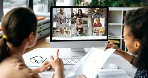 Twee medewerkers voeren via WeSeeDo een videogesprek met zes andere deelnemers.